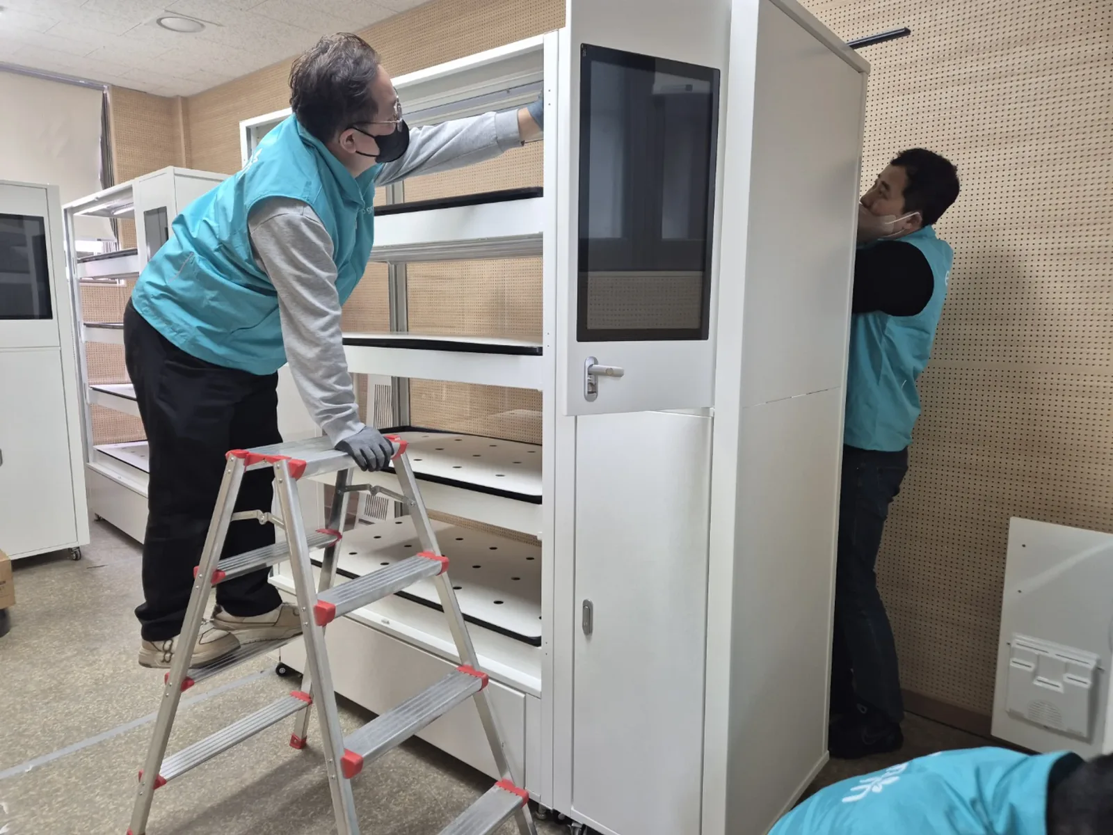 실내수직농장 재배랙 상단 설비를 사다리에서 점검하는 기술자